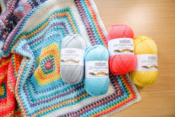 Linen stitch crochet blanket with balls of yarn.