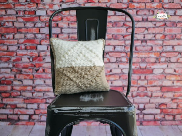 Crochet pillow on a black chair.