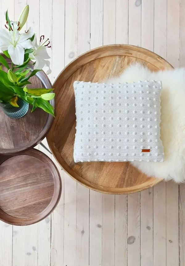 White crochet pillow cover with bobble stitch detail.