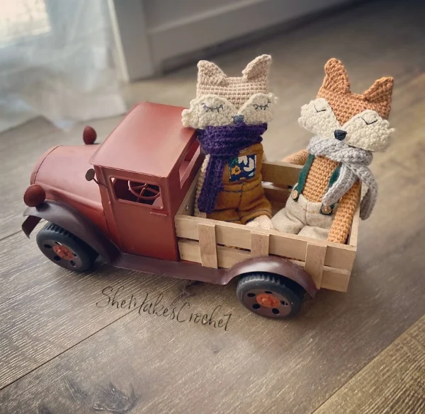 Two crochet fox amigurumi in a toy truck.