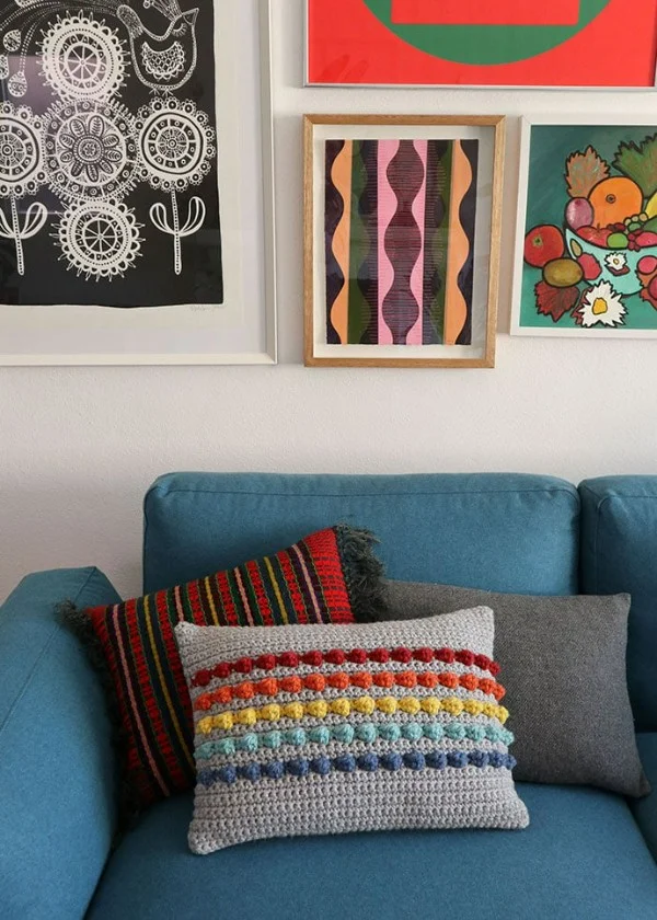 Crochet pillow with rainbow bobbles.