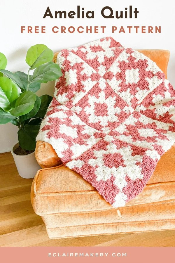 A pink and white C2C crochet blanket thrown across a couch.