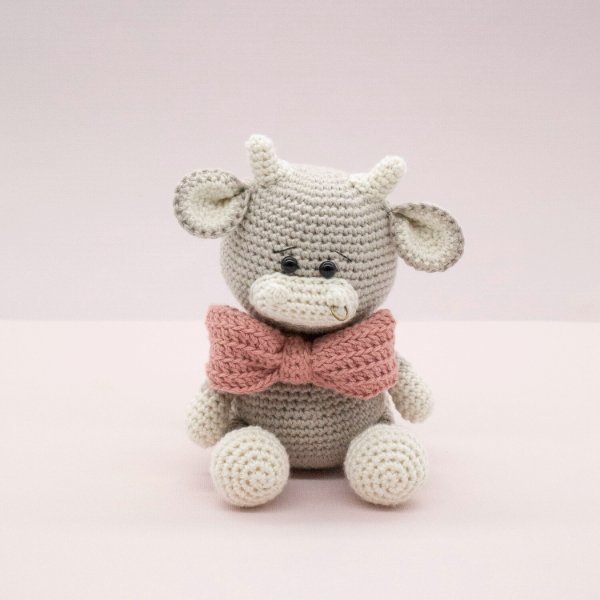 A little grey crochet bull with a pink bow tie.