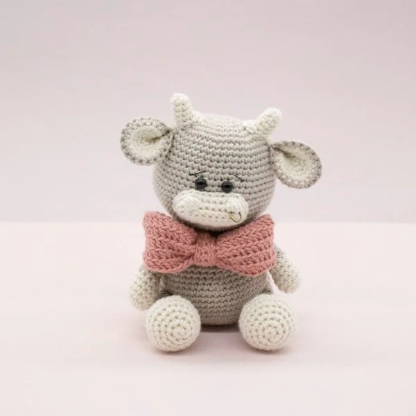 A little grey crochet bull with a pink bow tie.