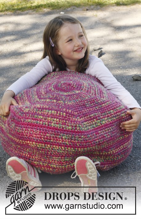 A child holding a large pink crochet ottoman.