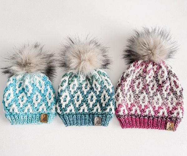 Three mosaic crochet beanies in a row, from smallest to largest.