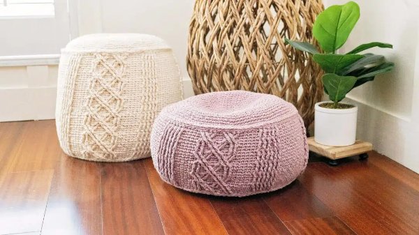 One pink and one cream coloured crochet floor poufs.