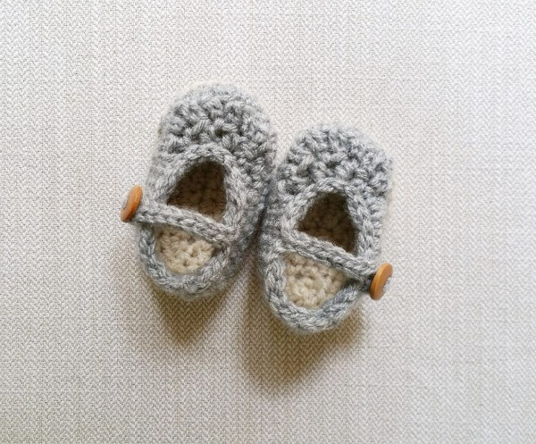 Grey crochet Mary Jane baby shoes with wooden buttons.