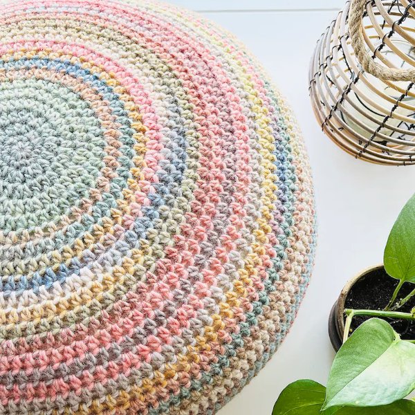 A crochet pouf in muted pastel rainbow colours.