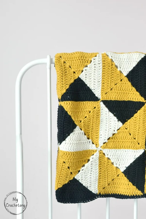 Geometric pinwheel crochet blanket in black, white, and yellow.
