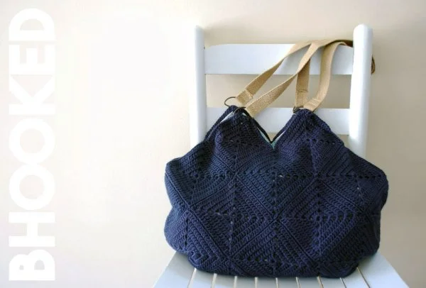 Navy granny square crochet bag on a white chair.