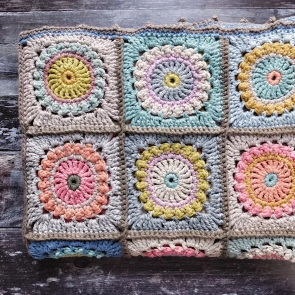 Granny square baby blanket in muted pastels.