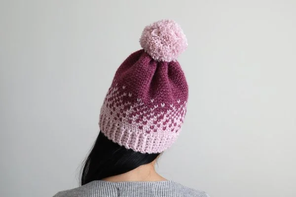 Back view of a woman wearing a pink Fair Isle crochet beanie.