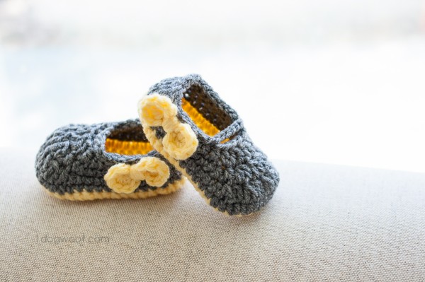 Grey crochet Mary Jane baby shoes with yellow bows.