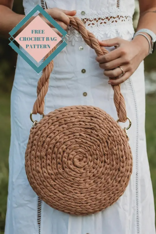 closeup of a woman holding a brown crochet bag with twisted strap.