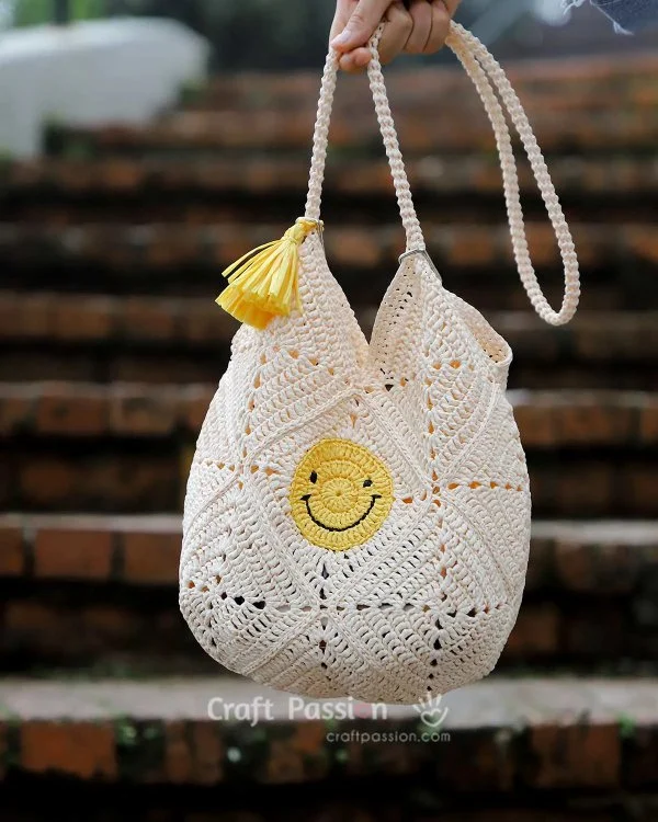 A crochet bag with a crocheted smiley face motif.
