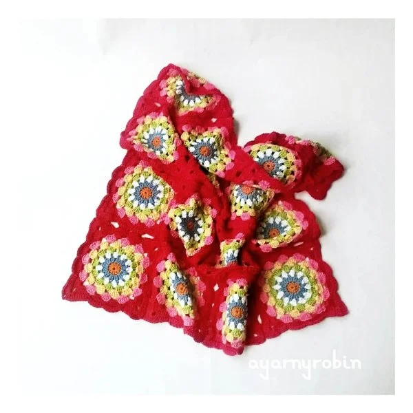 Granny square baby blanket with red backgrounds.