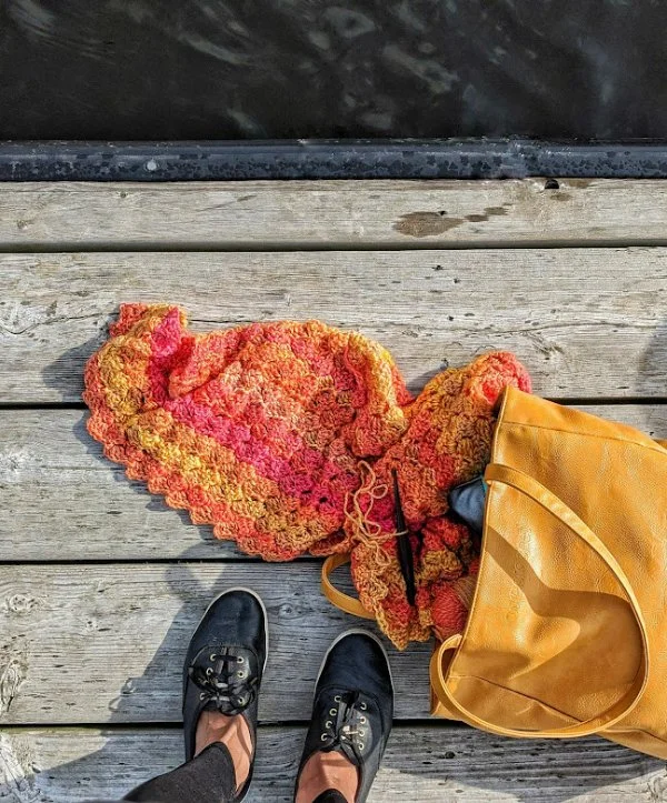 A c2c crochet blanket spilling out of a leather tote.