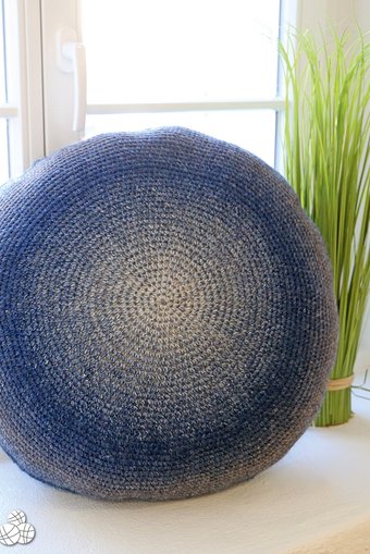 Blue gradient crochet floor cushion standing on its side.