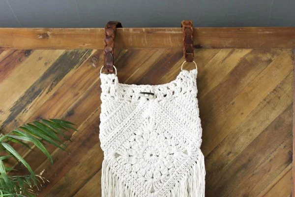 Small white crochet bag with repurposed leather belt handles.