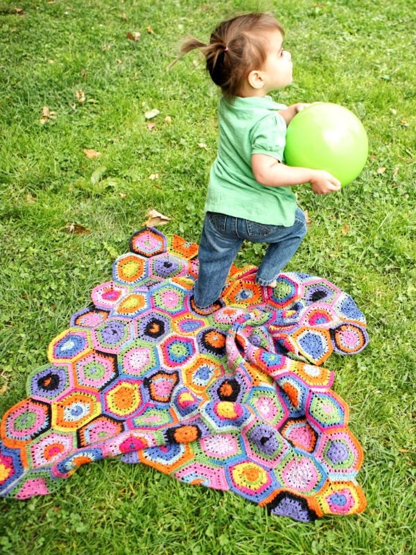 Toddler playing with ball on crochet blanket.