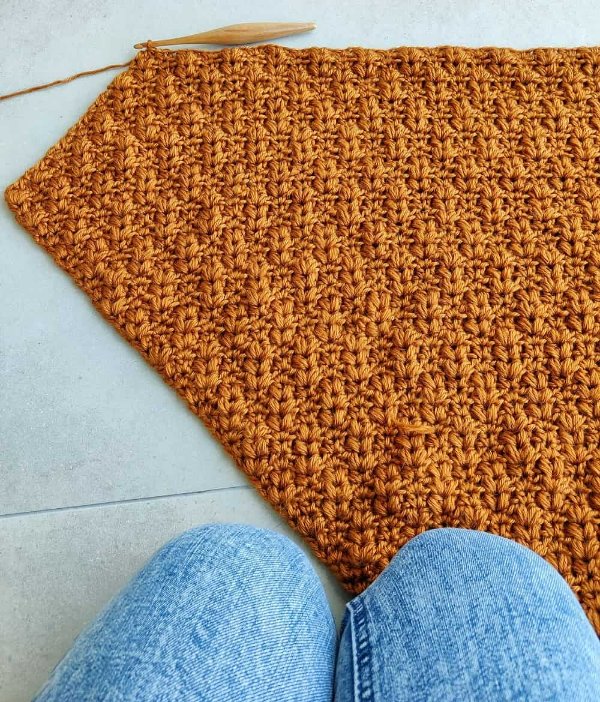 Half-finished c2c crochet blanket with a crochet hook.