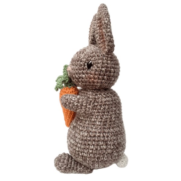 A brown crochet rabbit holding a carrot.