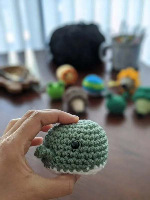A small amigurumi whale held in someones  hand.