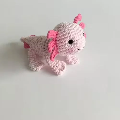 A pink baby axolotl crochet toy.