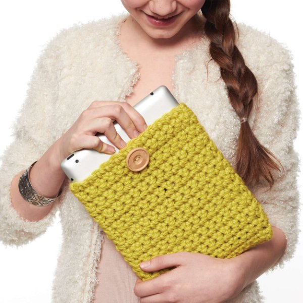 A woman getting an iPad out of a yellow crochet iPad cover.