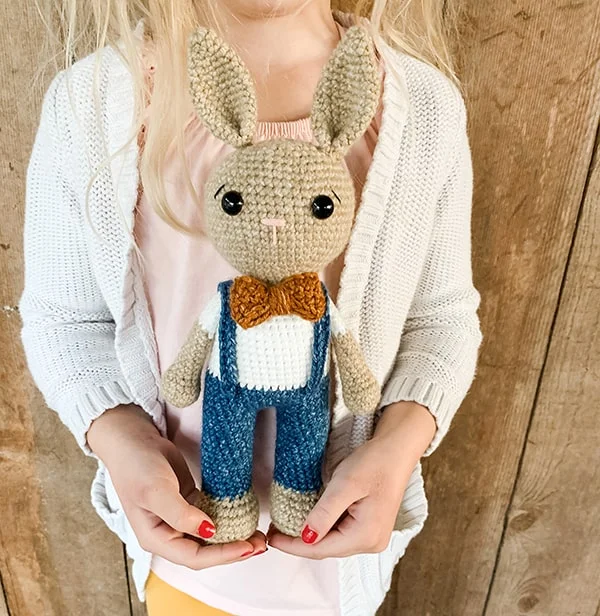 Crochet bunny toy dressed as a boy with overalls and a bowtie.