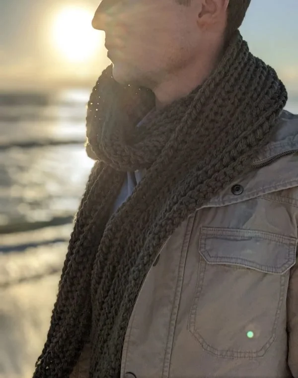 A man wearing a chunky ribbed crochet scarf.