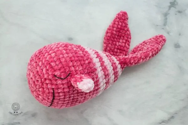 A pink crochet whale stuffie with stripes.
