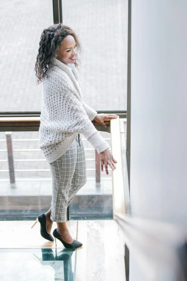 A side view of a woman in a white crochet shrug and heels.
