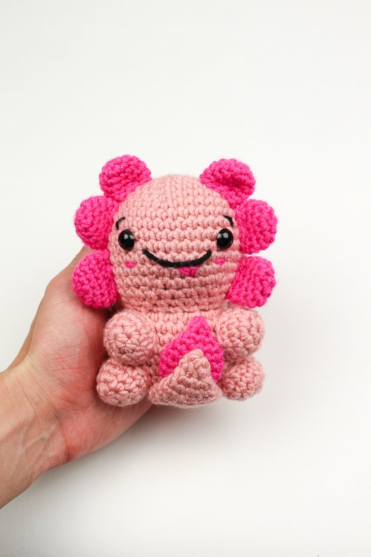 A pink axolotl amigurumi with neon pink fins.