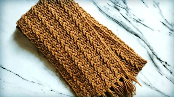 A mustard coloured crochet cable stitch scarf.