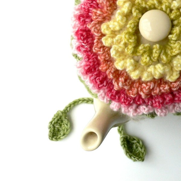 A frilly floral crochet tea cozy on a teapot.
