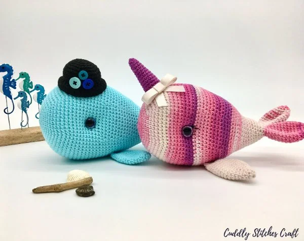 A blue crochet whale in a black bowler hat and a pin striped crochet narwhal.