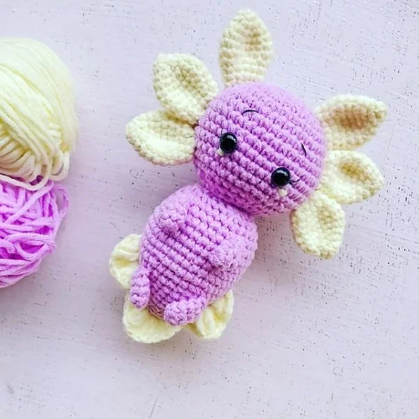 A pink and white crochet baby axolotl.