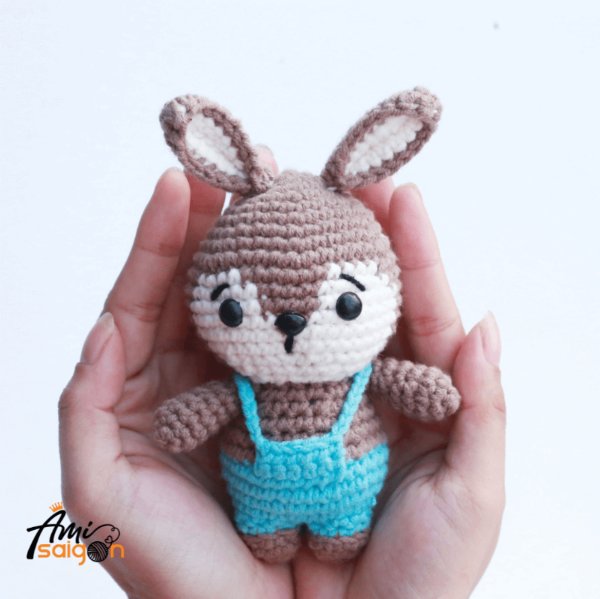 A crochet bunny wearing blue overalls.