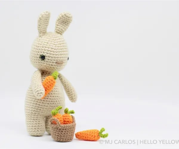 An amigurumi rabbit with a basket of carrots.