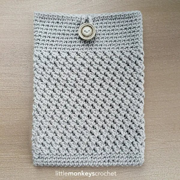 A grey crochet tablet sleeve with a large button.