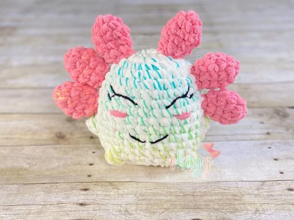 A crochet axolotl plushie with pink fins.