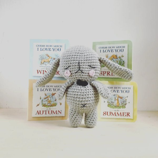 Grey crochet bunny in front of four children's books.