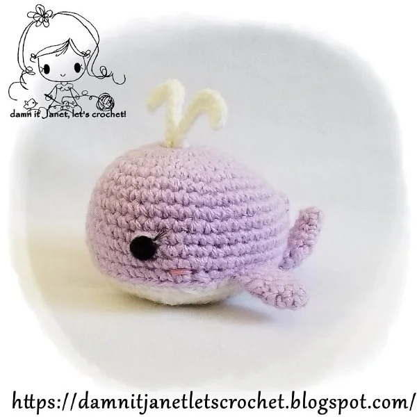 A lavender coloured crochet whale with a white spout.