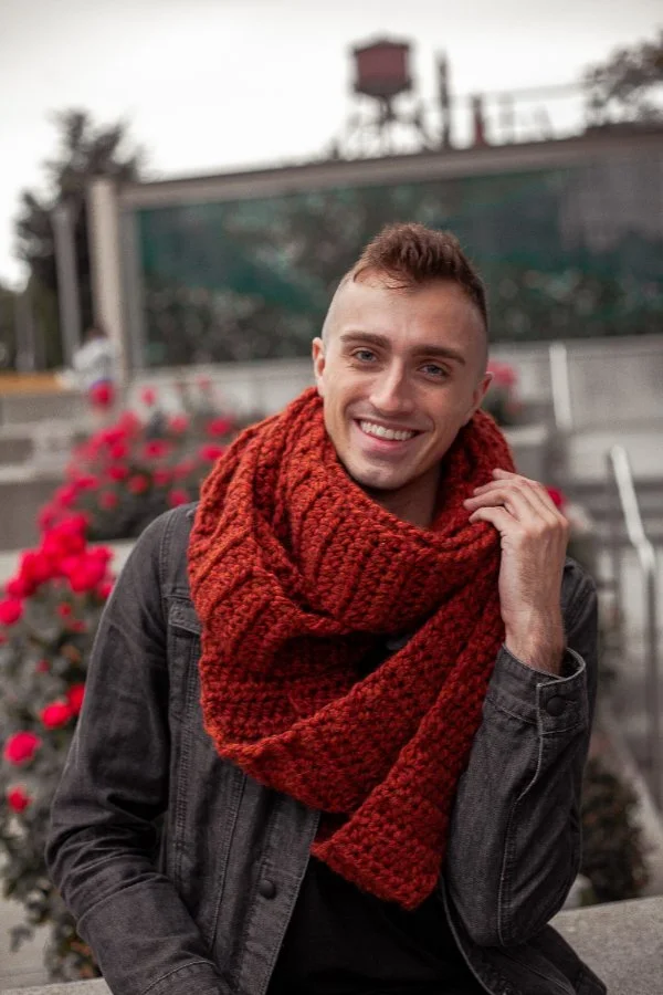 A man wearing a chunky red crochet scarf.