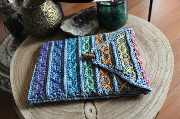 A crochet iPad sleeve with surface crochet detail on a coffee table.