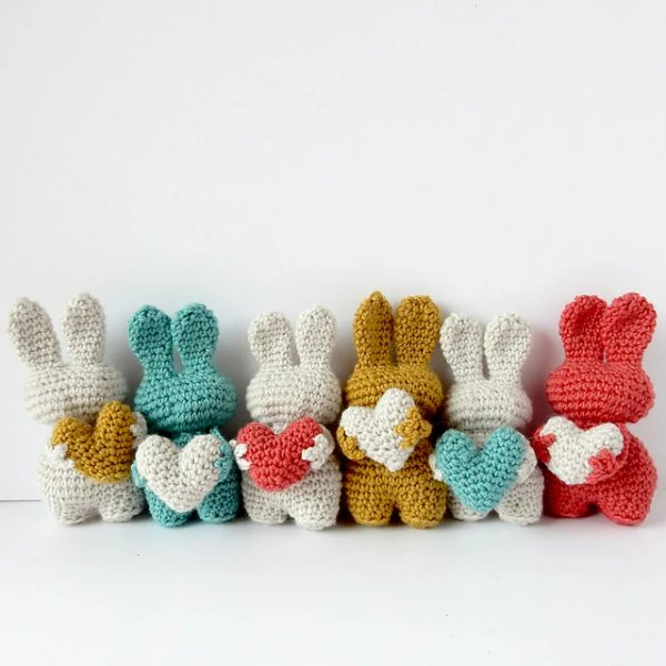 A row of crochet bunnies holding love hearts.