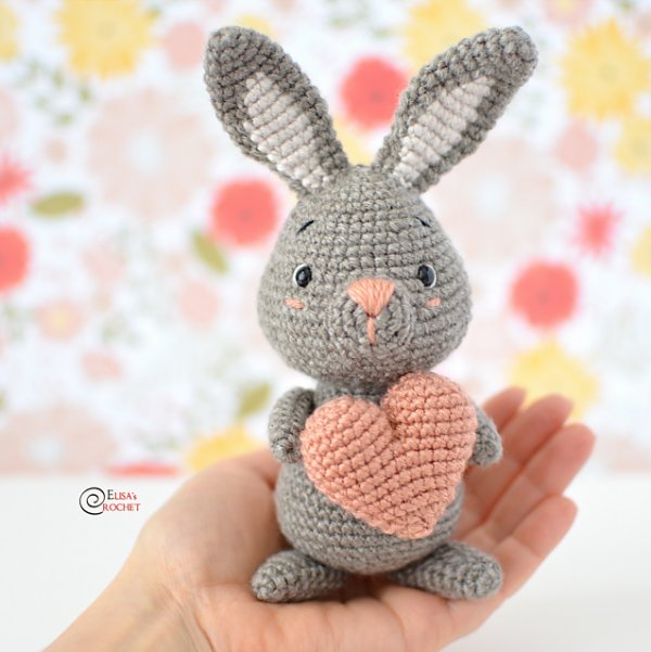 Grey amigurumi rabbit with a pink love heart.