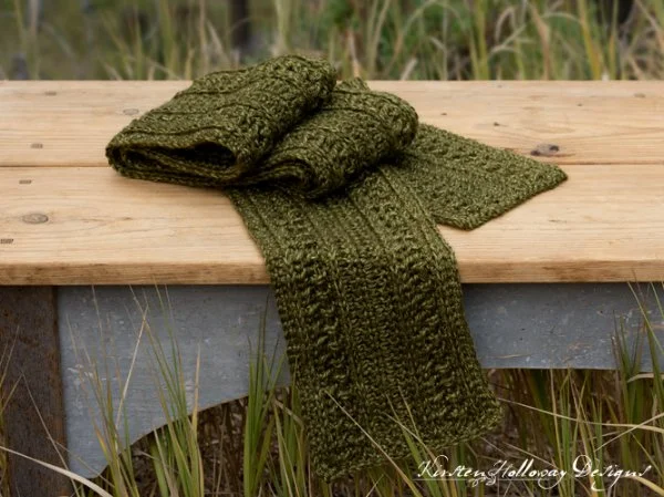 A green, textured crochet scarf on a timber bench.